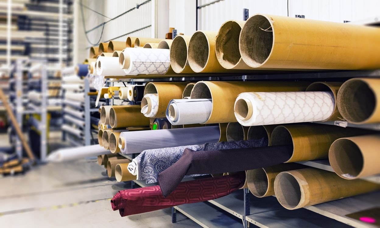 Rows of finished fabric rolls stored inside a textile production facility