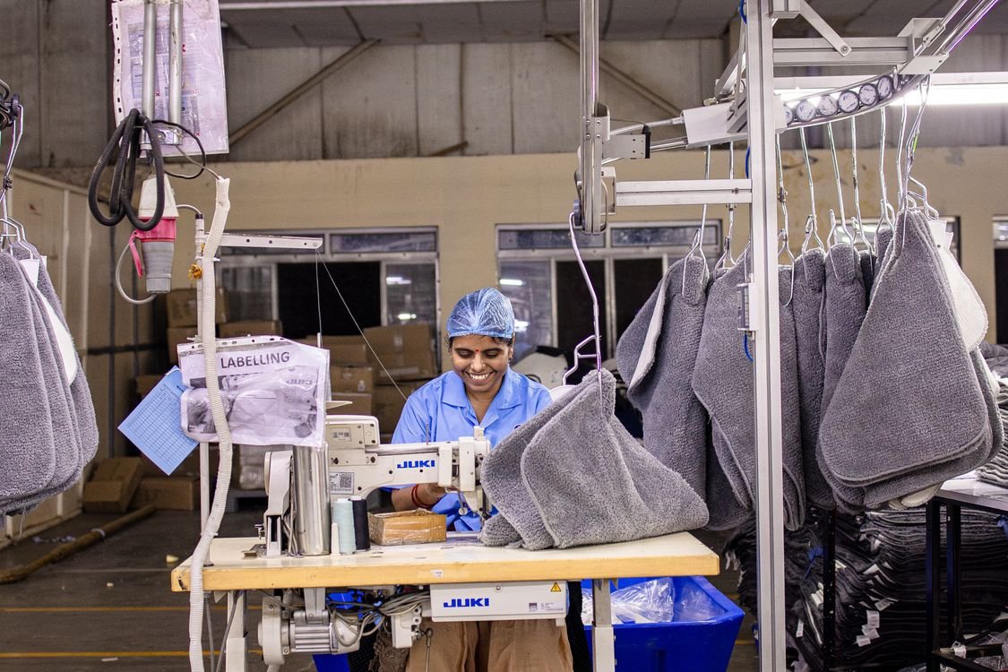 Textile factory worker operating a sewing machine on the production floor
